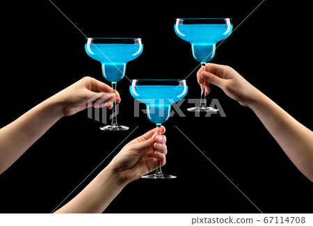 Set of hands holding blue curacao margarita glass isolated on black. 67114708