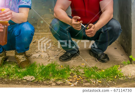 alcoholics, smokers and bad guys sit on the street near cigarette butts alcoholics, smokers and bad guys sit on the street near cigarette butts 67114730