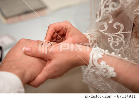 Hands of the newlyweds at the wedding ceremony of dressing the wedding rings. 67114911
