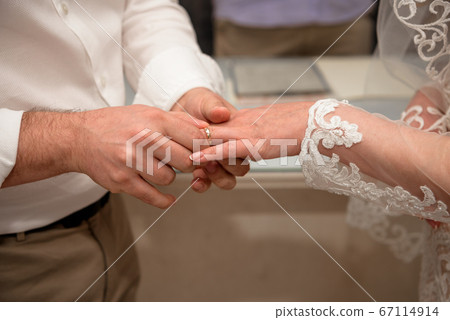 Hands of the newlyweds at the wedding ceremony of dressing the wedding rings. Hands of the newlyweds at the wedding ceremony of dressing the wedding rings. 67114914