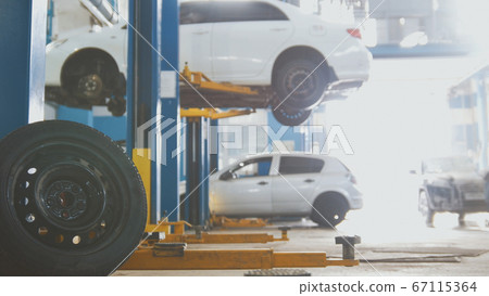 Car in auto service lifting for repairing, mechanics in garage Car in auto service lifting for repairing, mechanics in garage 67115364