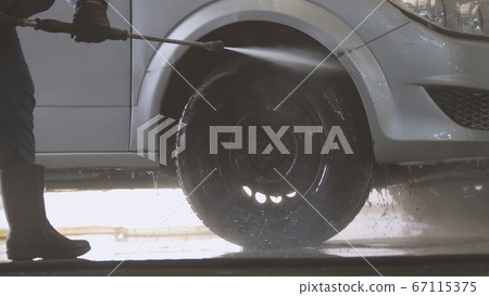 Worker washing the car salon with water hose Worker washing the car salon with water hose 67115375