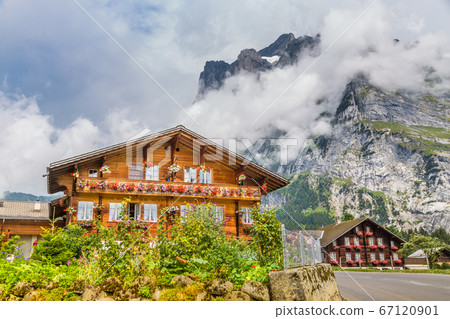 Traditional farmhouses with mountain peaks in Grindelwald, Switzerland 67120901