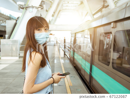 business woman wearing face mask at train station 67122087