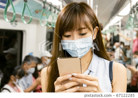 young Asian woman wearing surgical mask in the young Asian woman wearing surgical mask in the 67122285