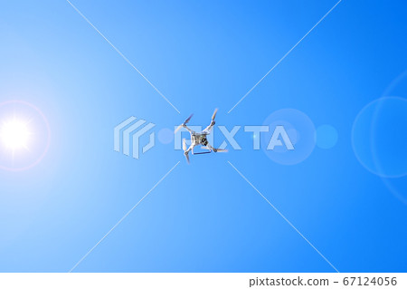 Drone flying in sunshine on blue sky background Drone flying in sunshine on blue sky background 67124056