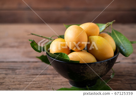 Thai plango fruit or marian plum on wood plate 67125359