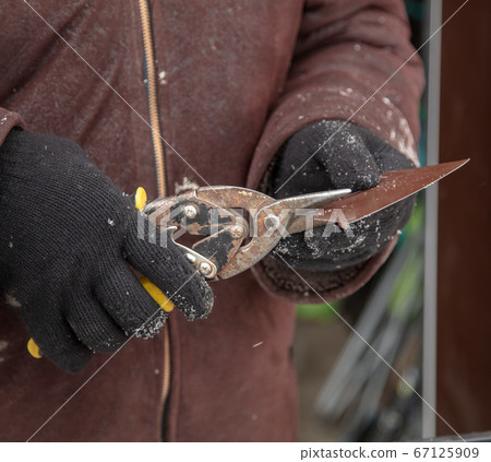 Worker scissors metal at a construction site 67125909