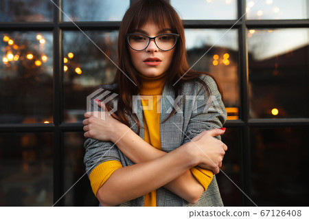 Beautiful dreamy girl in stylish sharp glasses. Near the shop window Beautiful dreamy girl in stylish sharp glasses. Near the shop window 67126408