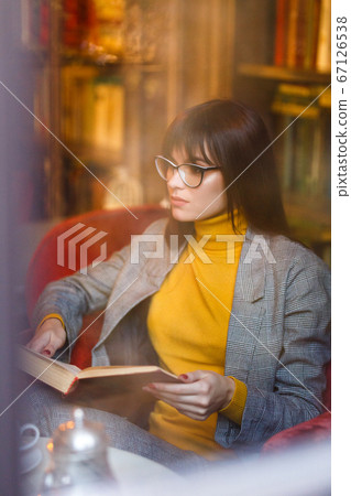 Beautiful dreamy girl in stylish sharp glasses. In the library. 67126538