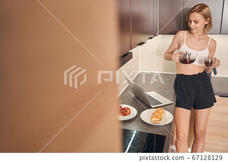 Blonde lady leaning against the kitchen countertop Blonde lady leaning against the kitchen countertop 67128129