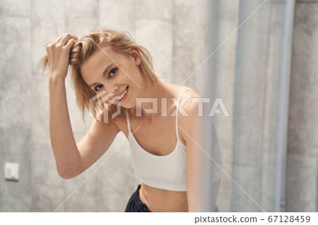 Lady with a happy smile standing in the bathroom 67128459