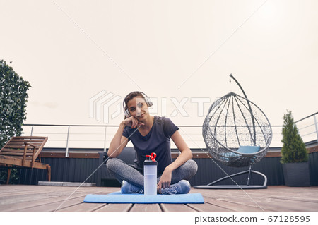 Beautiful sporty woman sitting on yoga mat 67128595