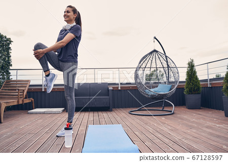 Cheerful young woman in sportswear working out outdoors 67128597