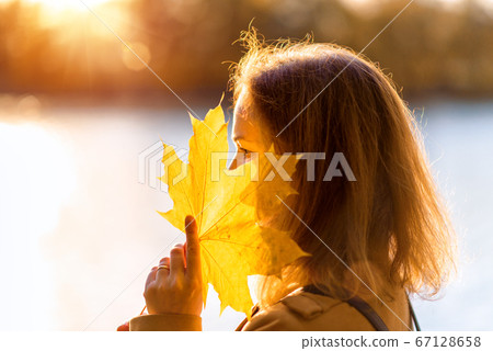 Autumn maple leaf in hand of pretty woman, Autumn maple leaf in hand of pretty woman, 67128658
