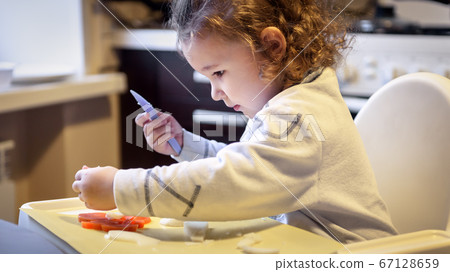 Child cuts carrots and potatoes in kitchen, pretty 67128659