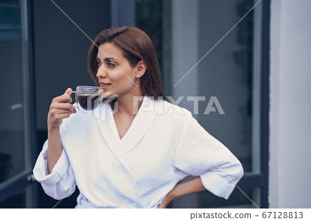 Beautiful young woman drinking coffee on balcony 67128813