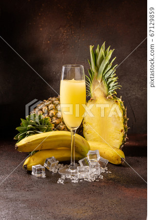 Delicious cold refreshing ananas smoothie drink in cocktail glass with banana Delicious cold refreshing ananas smoothie drink in cocktail glass with banana 67129859