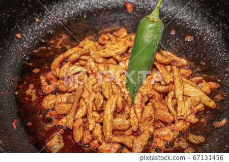 fried spicy slices of pork meat in a pan with 67131456