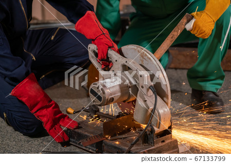 Professional mechanic man is cutting steel metal with rotating carbon blade Professional mechanic man is cutting steel metal with rotating carbon blade 67133799