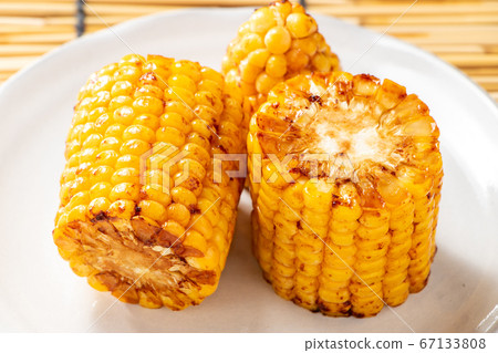 烤玉米(烤黃油醬油)。在背景窗簾中的夏天圖像。 烤玉米(烤黃油醬油)。在背景窗簾中的夏天圖像。 67133808