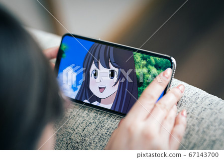 A woman watching an animation on a smartphone [Image] 67143700