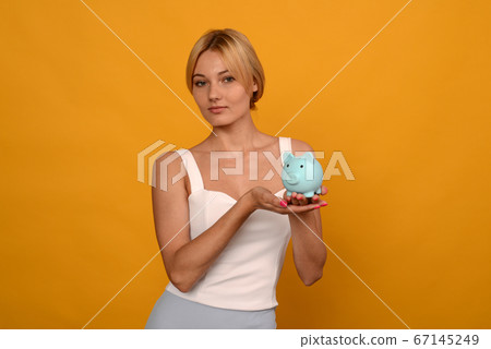 Beautiful young girl holding a pig piggy bank on Beautiful young girl holding a pig piggy bank on 67145249