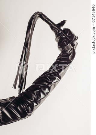 Leather whip in female hand isolated on a white 67145640