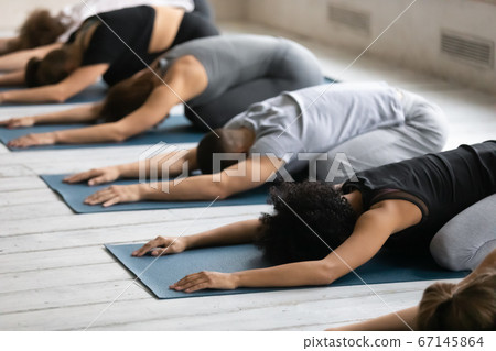 Young diverse people relaxing on floor mat in child pose. Young diverse people relaxing on floor mat in child pose. 67145864