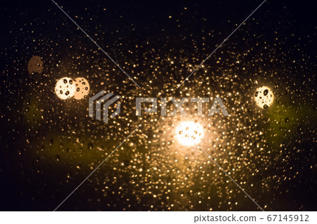 Drops of rain on window glass, lanterns in the 67145912