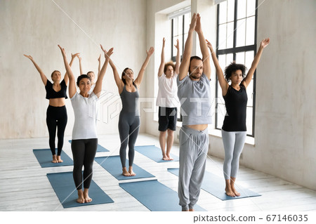 Happy young mixed race people doing surya namaskar exercises. 67146035