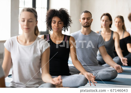 Young beautiful peaceful african american woman meditating with diverse people. Young beautiful peaceful african american woman meditating with diverse people. 67146043