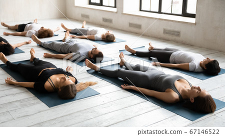 Diverse fit people relaxing in renovative savasana pose. Diverse fit people relaxing in renovative savasana pose. 67146522