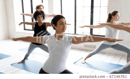Young fit indian ethnicity woman standing in virabhadrasana second position. Young fit indian ethnicity woman standing in virabhadrasana second position. 67146761