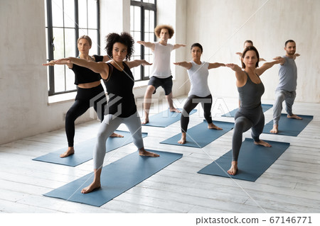 Happy mixed race people standing in warrior II pose. 67146771