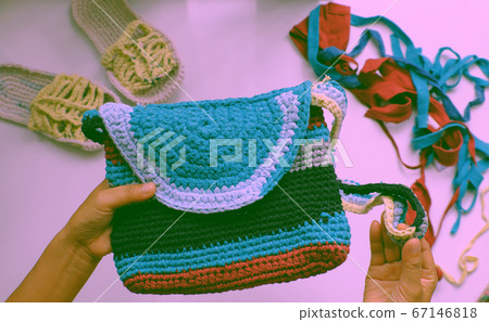 Close up from top view woman hand hold colorful handmade bag from recycle old t shirt Close up from top view woman hand hold colorful handmade bag from recycle old t shirt 67146818