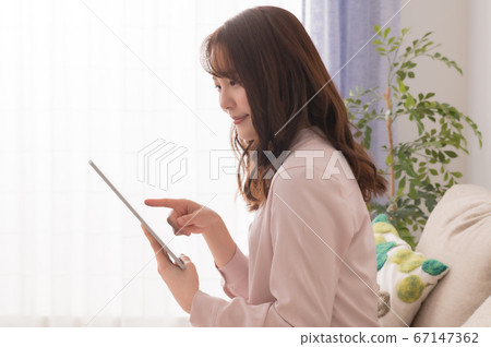 享受在平板電腦上的視頻的年輕女子 享受在平板電腦上的視頻的年輕女子 67147362