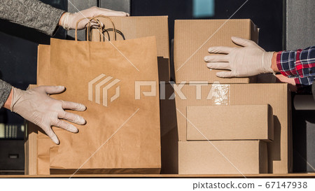 Couriers in protective gloves put parcels on the doorstep of the house 67147938