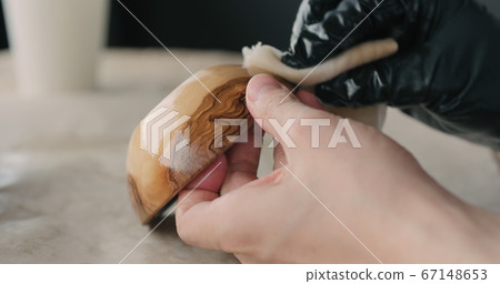 woodworker applying oil finish to olive wood bowl woodworker applying oil finish to olive wood bowl 67148653