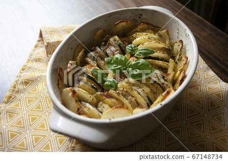 Hearty potato gratin bacon and zucchini,freshly served from the oven on a wooden table.Casserole food,vessel. Photo recipe. 67148734