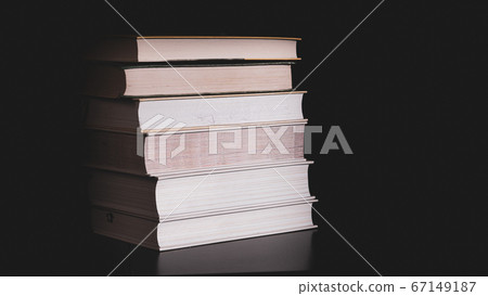 High messy stack of books on a black background with space for text message. High messy stack of books on a black background with space for text message. 67149187