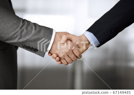 Business people in office suits standing and shaking hands, close-up. Business communication concept. Handshake and marketing Business people in office suits standing and shaking hands, close-up. Business communication concept. Handshake and marketing 67149485