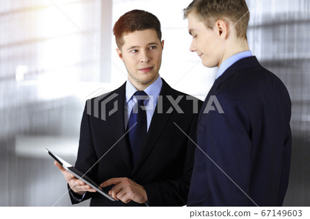 Business people discussing something while sitting in sunny office. Focus at businesswoman while talking to her male colleague Business people discussing something while sitting in sunny office. Focus at businesswoman while talking to her male colleague 67149603