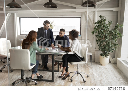 Serious multiethnic businesspeople gather at team meeting in boardroom Serious multiethnic businesspeople gather at team meeting in boardroom 67149738