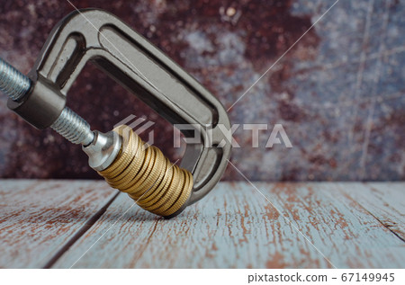stacking coin squeezing in a G-clamp as a financial crisis concept stacking coin squeezing in a G-clamp as a financial crisis concept 67149945