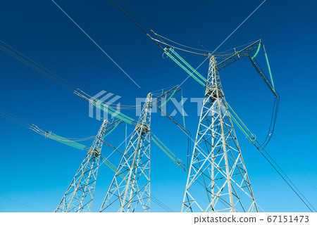 High voltage power lines with blue sky on the background, three electricity pylons High voltage power lines with blue sky on the background, three electricity pylons 67151473