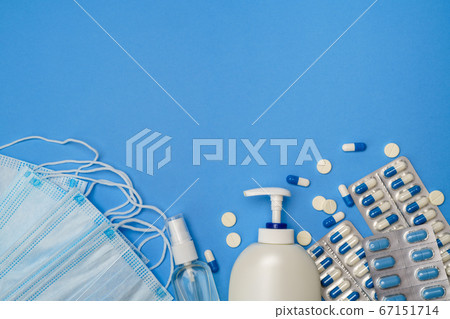 medical protective face masks, hand sanitizer gel and spay for hygiene and pills on blue background 67151714