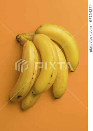 Bunch of ripe bananas on a bright orange background. Spotted overripe fruits. Vertical view. Abstract concept Bunch of ripe bananas on a bright orange background. Spotted overripe fruits. Vertical view. Abstract concept 67154274