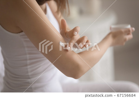Close up young woman applying moisturizing cream on arm Close up young woman applying moisturizing cream on arm 67156684