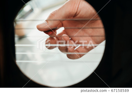 Hand Of Man Playing Acoustic Guitar Viewed From Inside Hole 67158589
